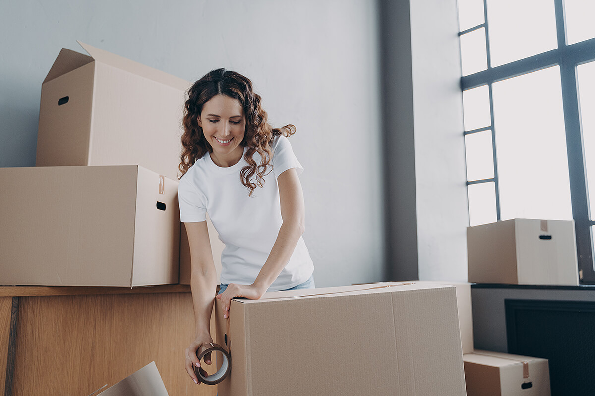 Young woman tapes up boxes ready to be moved into shipping container